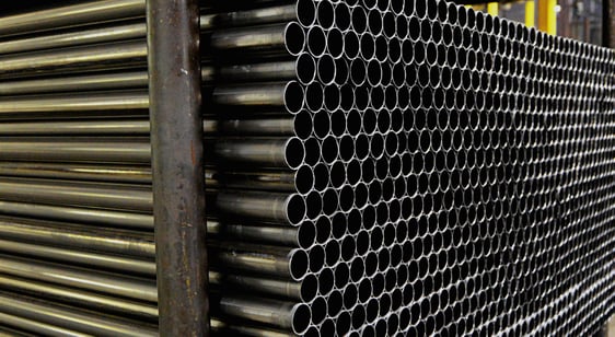 Round metal tubes stacked and stored in rows