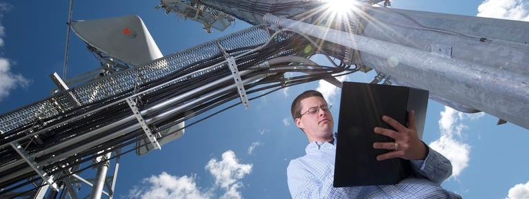 Engineer with a clipboard standing below a large metal structure