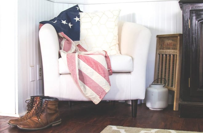 A pair of workboots in front of a chair with a patriotic blanket