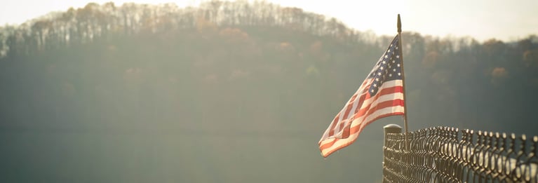 An American flag waving on a chain-link fence