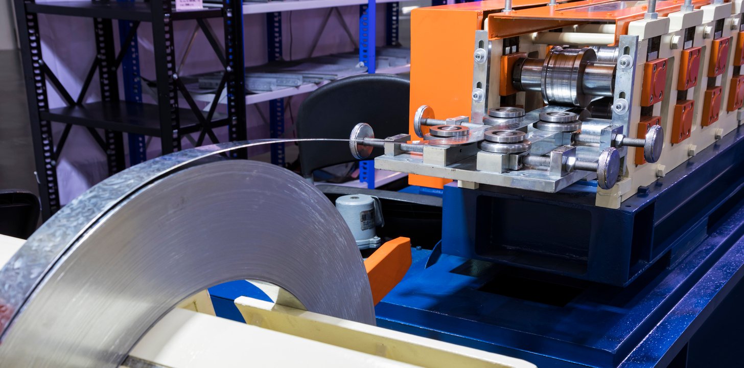 Aluminum sheet metal being fed through a rolling machine