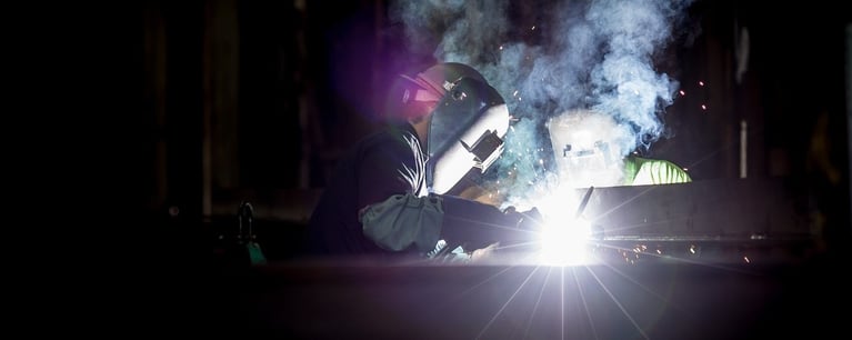 Welders create sparks and smoke in the dark