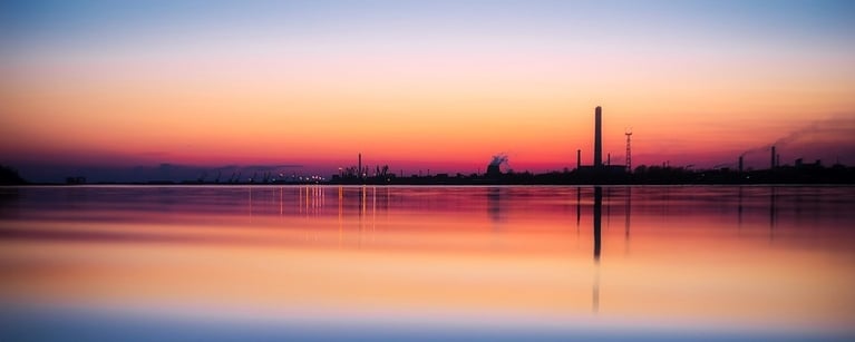 Industrial chimney across a sunset lake