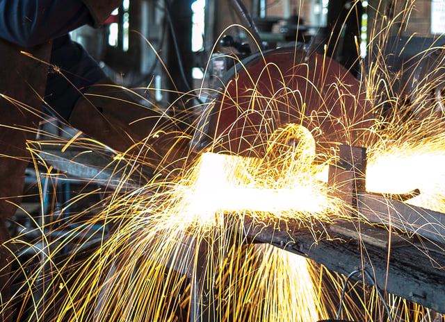 Sparks flying as an engineer works with sheets of metal